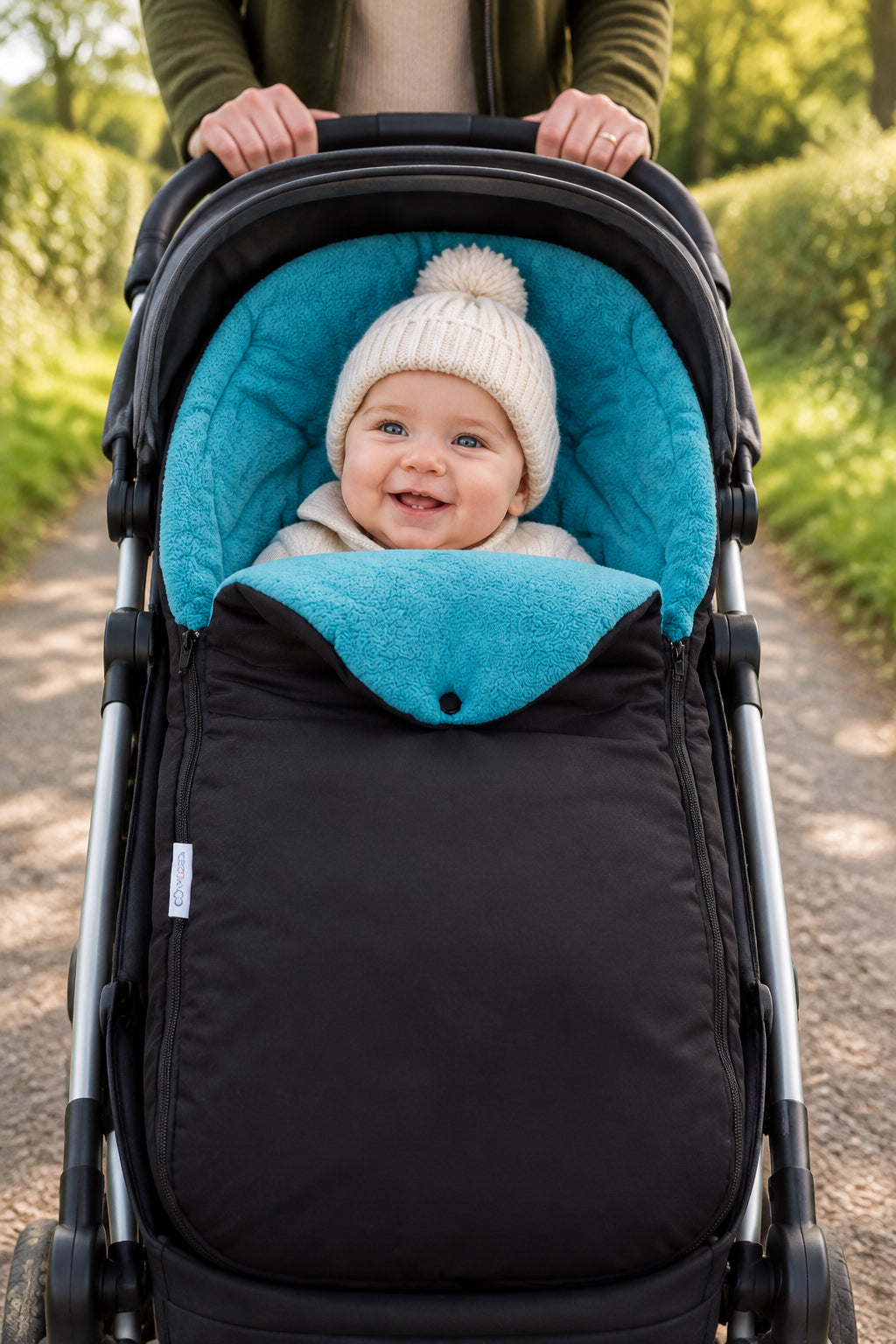 Turquoise baby footmuff on a black bag against a white background